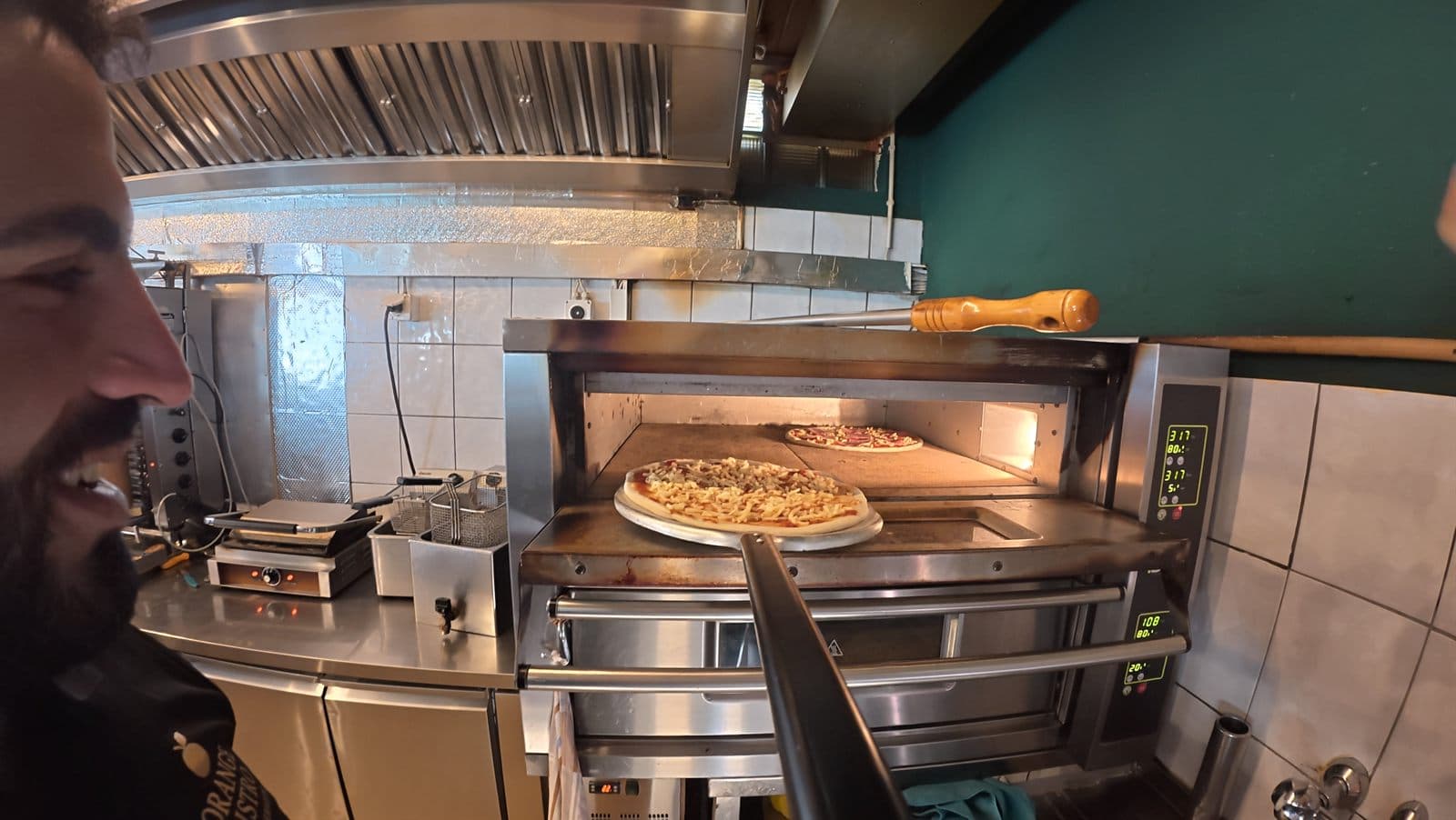 Pizza wird in den Steinofen geschoben